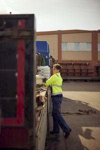 Female worker unloading goods from truck outside factory on sunny day