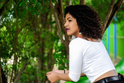 Young woman smiling against trees