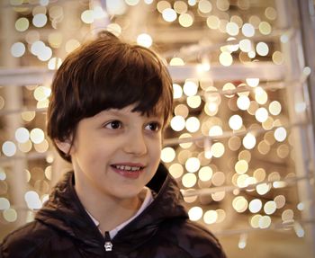 Smiling boy looking away against illuminated lights