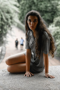 Portrait of young woman sitting on tree