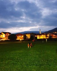 People on illuminated buildings against sky