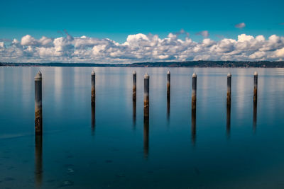 Wooden posts in sea against sky