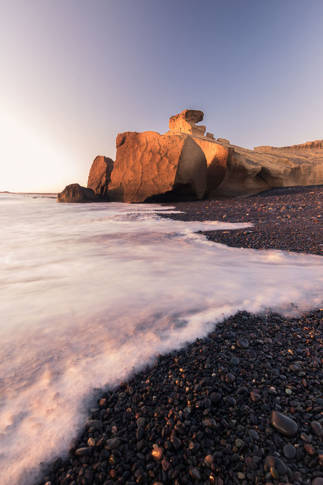 ROCK FORMATION ON SHORE AGAINST CLEAR SKY