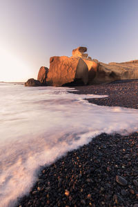 Rock formations on shore against clear sky