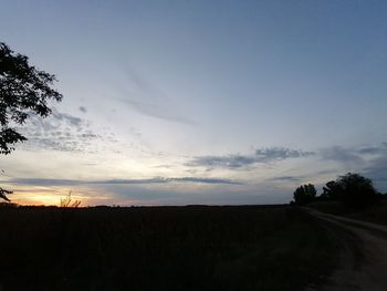 Scenic view of silhouette field against sky at sunset