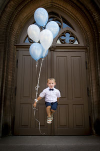 Full length portrait of boy jumping against door