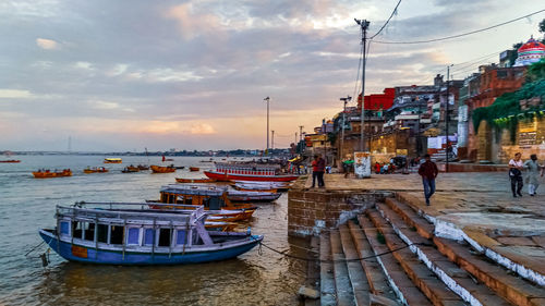 Boats moored at harbor during sunset