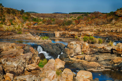 Rocks by river against sky