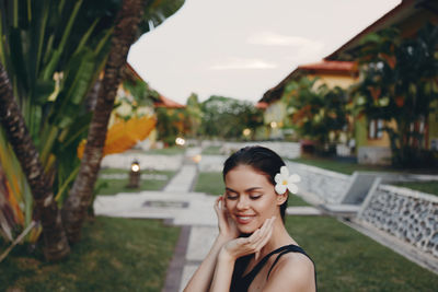 Portrait of young woman standing against trees