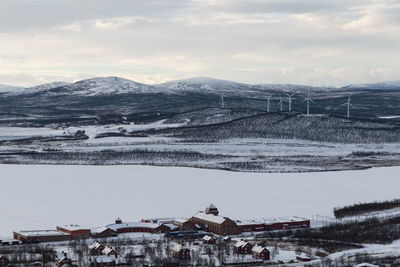 High angle view of town and wind turbines against sky in winter.
