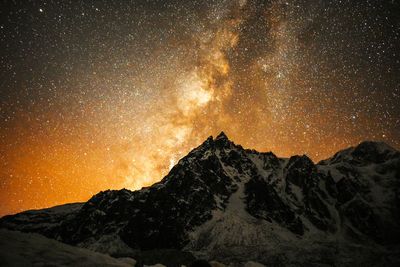 Low angle view of snowcapped mountains against sky at night