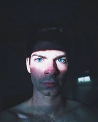 Sunlight falling on shirtless young man with nose ring in darkroom