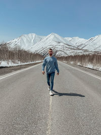Full length of man walking on road against snowcapped mountain