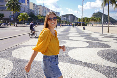 Woman walking along copacabana beach promenade and turns to the camera, rio de janeiro, brazil