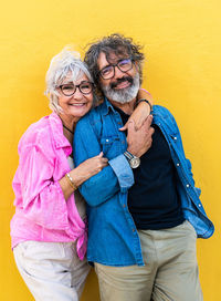 Portrait of smiling young woman standing against yellow wall