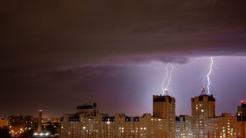 Lightning over illuminated buildings in city at night