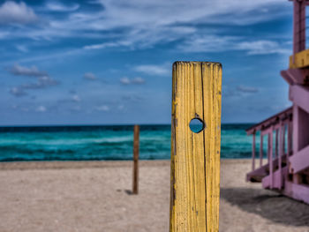 Wooden posts on beach against sky