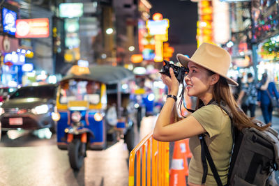 Woman standing on illuminated street at city