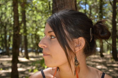 Close-up of woman looking away against trees