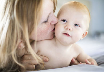 Close-up of cute baby girl lying on bed at home