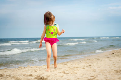 Full length of girl walking at beach against sky