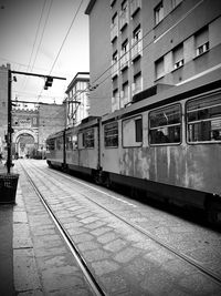 Train at railroad station in city against sky