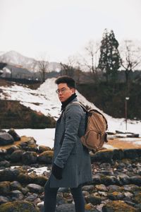 Side view of young man standing on rock