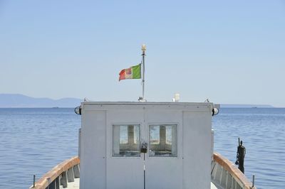 Flag on sea against clear sky