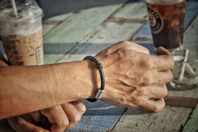 High angle view of man hand holding marijuana joint on table