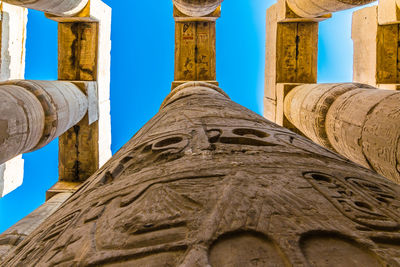 Columns with egyptian hieroglyphs in the karnak temple in luxor. looking up into the blue sky.
