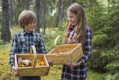 Brother and sister picking mushrooms in forest