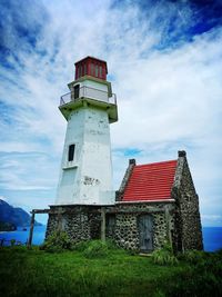 Low angle view of lighthouse by building against sky