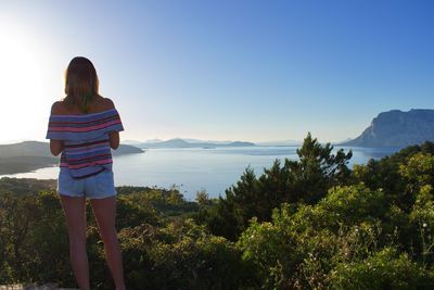 Rear view of woman looking at mountains against sky
