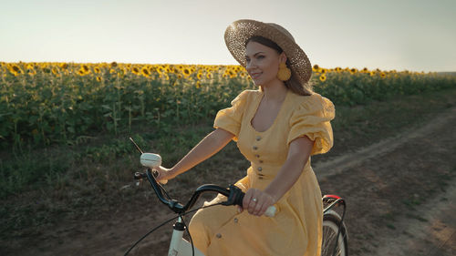 Portrait of young woman riding bicycle on field