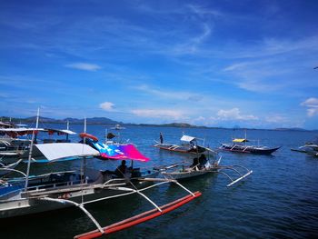 Boats moored in sea against blue sky