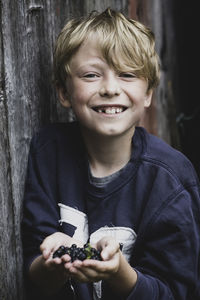 Portrait of happy boy holding blueberries