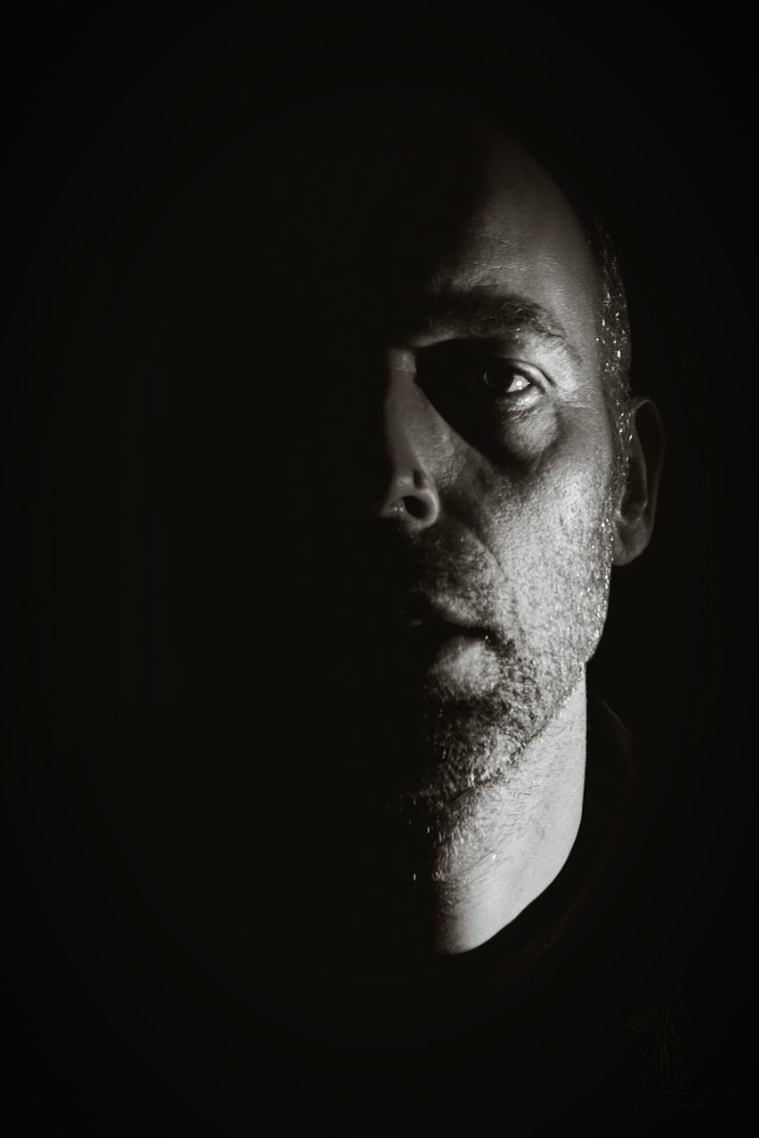 headshot, portrait, young adult, looking at camera, black background, studio shot, close-up, serious, human face, lifestyles, front view, indoors, young men, contemplation, person, mid adult, beard, leisure activity