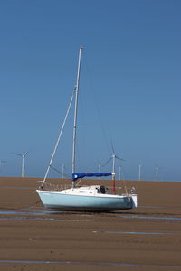 Sailboat on sea against clear blue sky