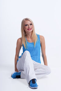 Portrait of young woman sitting against white background