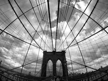 Low angle view of suspension bridge against cloudy sky