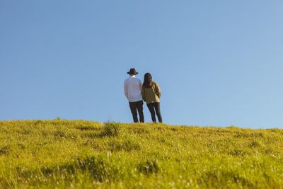 Rear view of man walking on field against clear sky