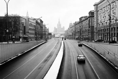 Cars on road in city against sky