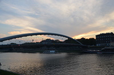 Bridge over river in city against sky during sunset