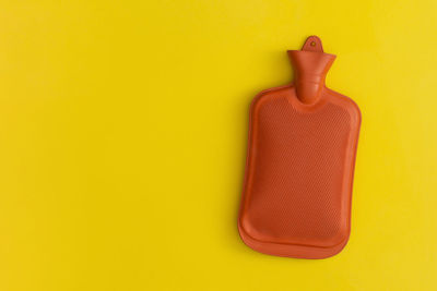 Hot water bottle on a yellow background. top view with copy space. flat lay.