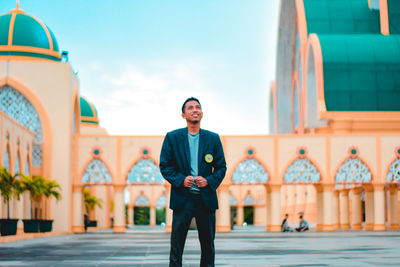 Portrait of young man standing against building