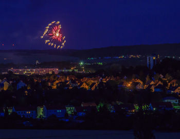 Firework display over illuminated buildings in city at night