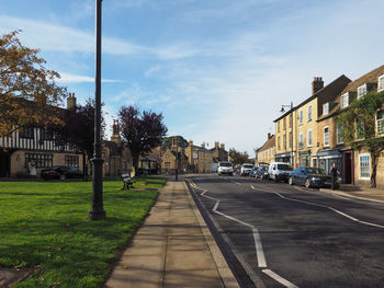 Road by buildings in city against sky