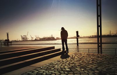 Silhouette man standing on shore against clear sky