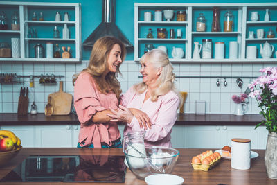 Smiling mother and daughter embracing at kitchen