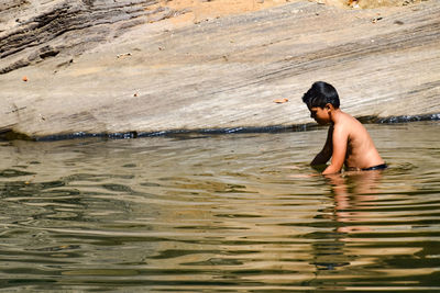 Full length of shirtless boy in lake